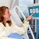 A graphic of a patient in bed using touchscreen menu ordering technology.
