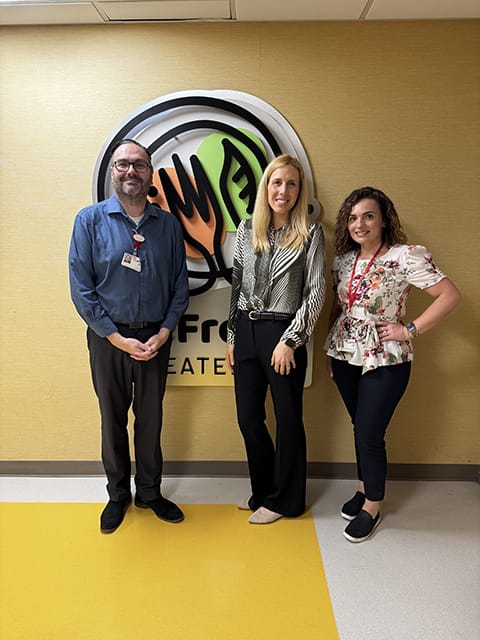A photo of Kevin Steffes (Food Services Director at Carle Foundation Hospital), Holly Illions (Sr. Account Relationship Manager at Computrition), and Teuta Selimi (Food Service Retail Operations Manager at Carle Foundation Hospital) in front of CFH's reFresh Eatery sign