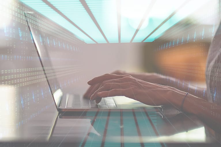 A profile shot of a pair of hands working on a laptop. The image is overlaid with another image of a server room.