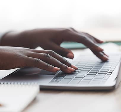 Closeup of a pair of hands typing on a laptop keyboard