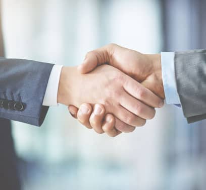 Two people dressed in suits shake hands.