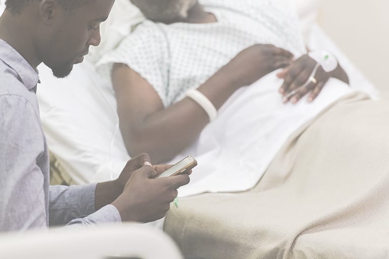 Patient's family member sitting in a chair using a phone for self-ordering meal.