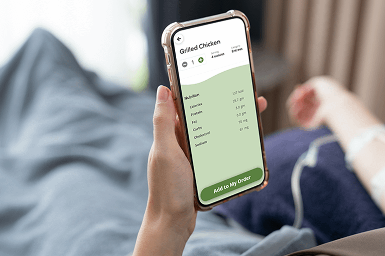 Patient in bed using their smartphone for self-ordering a grilled chicken meal.