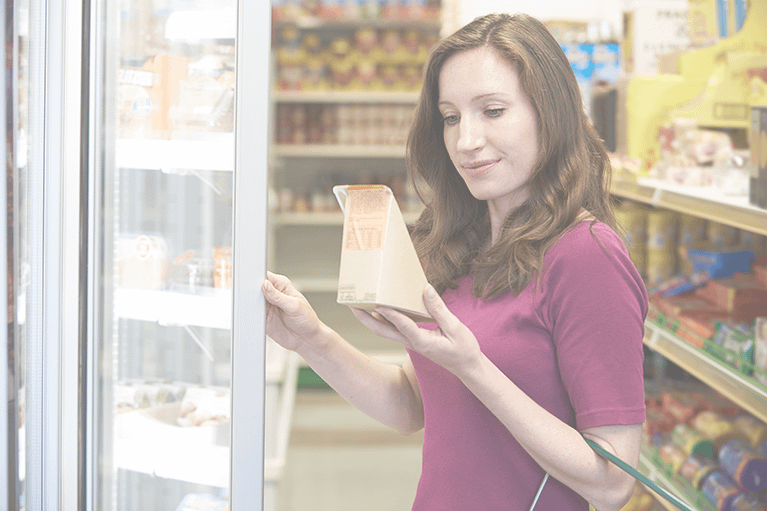 A woman examines a sandwich container with nutrition labeling as she shops for food.